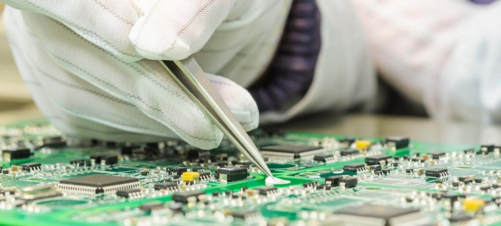 A gloved hand working on a circuit board